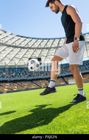 Jeune joueur de foot balle rebondissante sur jambe à stade Banque D'Images