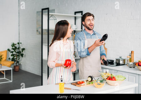 Couple à jongler avec les légumes pendant la cuisson dans la cuisine Banque D'Images