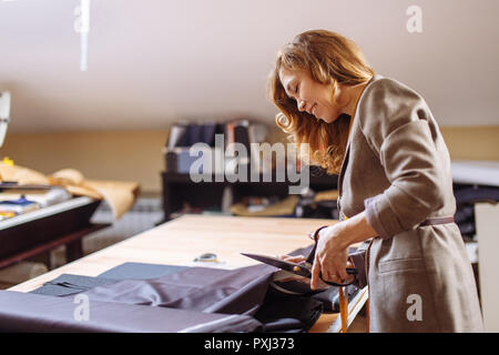 Designer de mode féminine travaillant sur tissu habillent avec accessoires de couture sur la table Banque D'Images