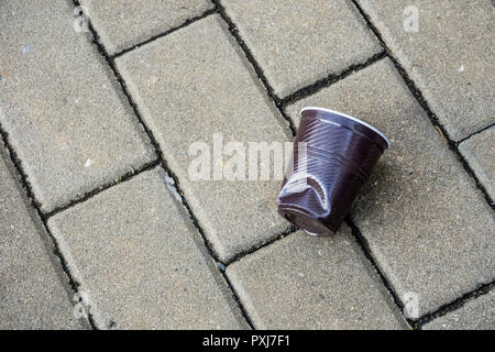 Tasse en plastique broyé et écrasé sur la pierre sur rue dans city show de déchets pollution atmosphérique, avec des paquets d'aliments de préparation rapide Banque D'Images