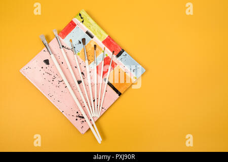 Ensemble de pinceaux à blanc sur une plaque de céramique colorée, sur fond jaune vif. Banque D'Images