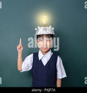 Chinois asiatique petite fille portant un casque de réalité virtuelle et montre de l'index jusqu'à l'encontre de la lampe de tableau noir vert Banque D'Images