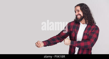 Portrait de profil Vue de côté bel homme sérieux avec barbe et black long cheveux bouclés en chemise rouge à carreaux avec commandes gestuelles et mains. je Banque D'Images