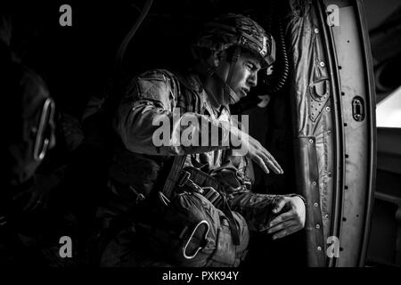 Un soldat de l'armée américaine accolades contre le vent à partir de la porte d'un côté ouvert U.S. Air Force C-130J Super Hercules affecté à la 37e Escadron de transport aérien à la base aérienne de Ramstein, en Allemagne, avant de sauter près de Sainte-Mère-Eglise, France, le 4 juin 2017. Cet événement commémore le 73e anniversaire du Jour J, le plus grand débarquement amphibie multinationale militaire opérationnel et airdrop dans l'histoire, et met en lumière l'engagement indéfectible des Etats-Unis d'alliés et partenaires européens. Dans l'ensemble, environ 400 membres des services d'unités en Europe et les États-Unis participent à des cérémonies D-Day 73 activités f Banque D'Images