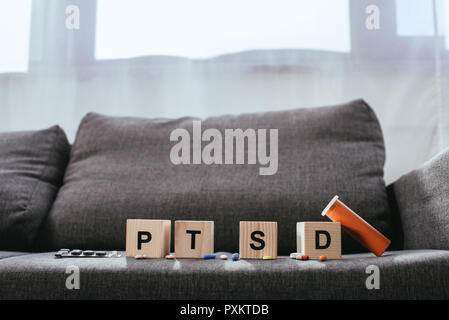 Cubes en bois avec le trouble de stress post-traumatique (SSPT) signes abréviation lying on couch avec divers comprimés Banque D'Images