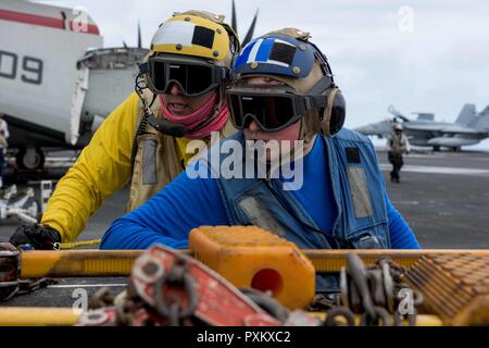 Mer des Philippines (6 juin 2017) l'Aviation maître de Manœuvre (manutention) 1re classe Melchor Valladares Aviation aide maître de Manœuvre (manutention) Airman Michael Clark park un aéronef dans le poste de pilotage de la marine de l'avant-déployé, porte-avions USS Ronald Reagan (CVN 76). Ronald Reagan, le groupe aéronaval du porte-étendard de 5, fournit une force prête au combat qui protège et défend les intérêts de maritime collective de ses alliés et partenaires dans la région du Pacifique-Indo-Asia. Banque D'Images