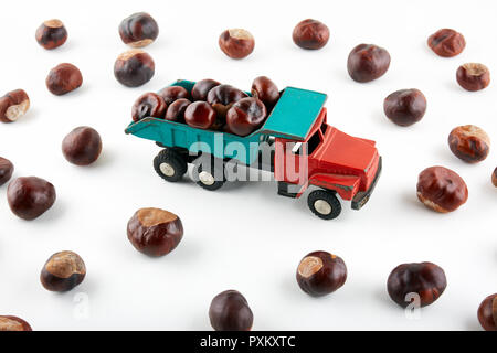 Châtaignes en camion jouet sur fond blanc. Banque D'Images