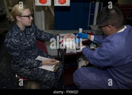 La NORFOLK (12 juin 2017) Hospital Corpsman Hospitalman Jose Ugarte prend un échantillon de 3e classe Corpsman Hôpital Katherine Janiak's blood pour présélectionner un au cours d'un programme de collecte de sang des Services à bord du navire d'assaut amphibie USS Wasp LHD (1). Le Wasp est actuellement en train de préparer leur prochain port d'attache passage à Sasebo, au Japon où elles sont destinées à soulager l'USS Bonhomme Richard (DG 6) dans la 7e flotte zone d'opérations. Banque D'Images