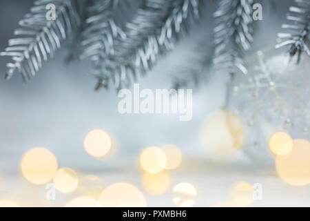 Noël fond argenté avec des branches de sapins floue flou artistique et taches feux garland Banque D'Images