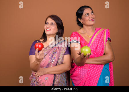 Deux heureux Indian woman holding apple en pensant Banque D'Images