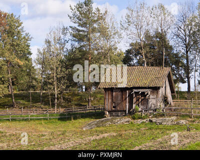 Remise délabrée sur le bord d'un champ vert, clôture en bois et divers arbres, un droit rural de Oslo Norvège Banque D'Images