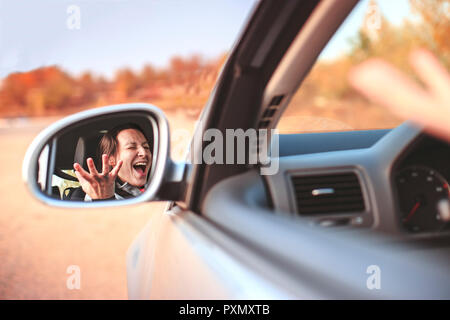 Belle jeune femme en colère crier dans sa voiture. La nervosité et l'anxiété en concept de la circulation automobile. Banque D'Images