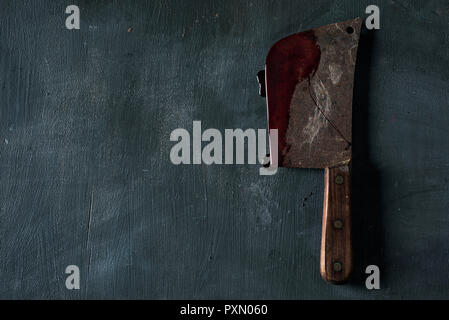 Portrait d'une vieille et Rusty couperet à viande pleine de sang, placé sur une surface rustique vert foncé, avec un espace vide sur la gauche Banque D'Images