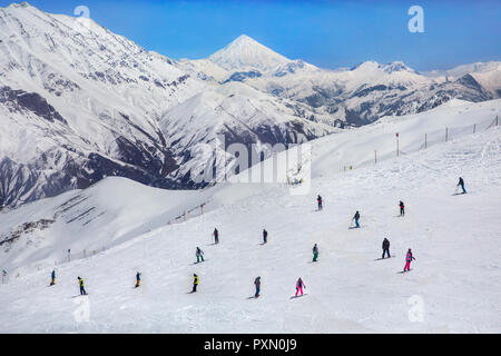 Vue sur les skieurs et le Mont Damavand depuis la station de ski de Dizin à Téhéran, Iran. Banque D'Images