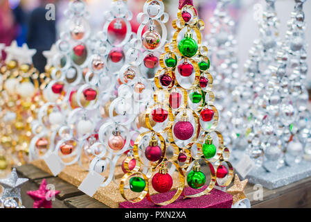 L'argent métallique décoratif et moderne d'or lacy les arbres de Noël avec des boules rouges et vertes sur la table en bois sur la lumière d'arrière-plan flou avec copie espace pour Banque D'Images