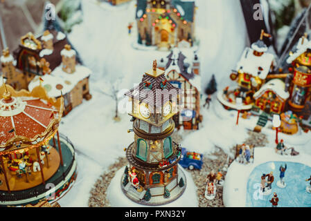 Noël jouet miniature en céramique avec ville couverte de neige et le modèle de marcher les gens. Les petites fêtes de village avec tour de l'horloge. Retro effet de filtre. Selec Banque D'Images