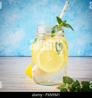 Feuilles de menthe limonade jar Coctail table en bois naturel de l'eau fond bleu citron cuisine maison soda boisson avec tranches de fruits et de paille est pop Banque D'Images