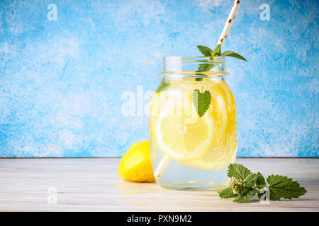 Feuilles de menthe limonade jar Coctail table en bois naturel de l'eau fond bleu citron cuisine maison soda boisson avec tranches de fruits et de paille est pop Banque D'Images