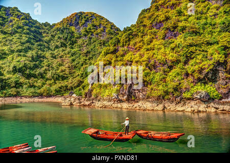 Méconnaissable vietnamienne barques qui amènent les touristes voyageant à l'intérieur de la grotte de calcaire de l'île calcaire avec en arrière-plan en été à la baie d'Halong. Le Vietnam. Banque D'Images