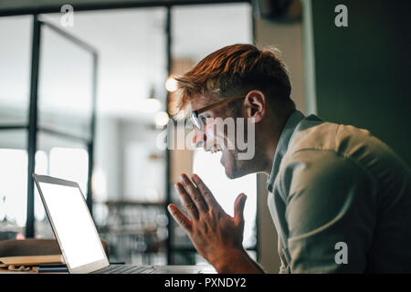 Young man using laptop, rire happly Banque D'Images
