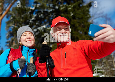 Happy senior couple pendant leur selfies formation sports d'hiver dans la forêt Banque D'Images