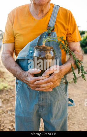 Senior man holding glass jar avec le sol et la croissance de carotte Banque D'Images