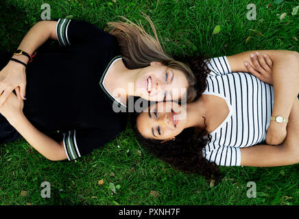 Deux copines se détendre dans un parc, lying on grass Banque D'Images