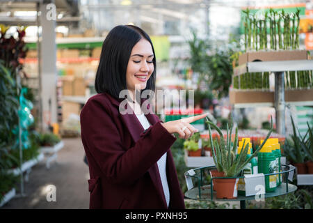 Chauffeur particulier femme avec panier en choisissant les plantes dans un centre de jardinage Banque D'Images