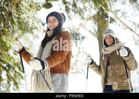 Taille portrait of happy young couple le ski en hiver et des forêts, l'accent sur femme en face Banque D'Images