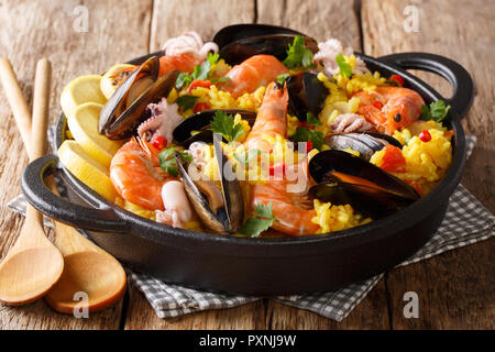 Des plats fraîchement préparés avec la paella, moules, crevettes, poissons, et le bébé octopus servi dans une poêle sur une table de bois horizontal. Banque D'Images