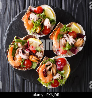 Salade de fruits de mer gastronomique restaurant de crevettes, poulpe bébé, moules, calmars et de pétoncles en coquilles de mer gros plan sur la table. haut Vue de dessus Banque D'Images