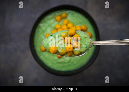 Bol de gaspacho vert avec avocat et curcuma pois chiches rôtis, sur une cuillère, close-up Banque D'Images