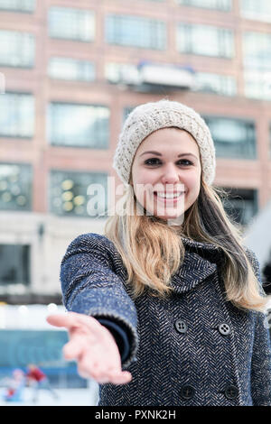 Jolie blonde jeune femme portant chapeau de laine en hiver, reaching out part Banque D'Images