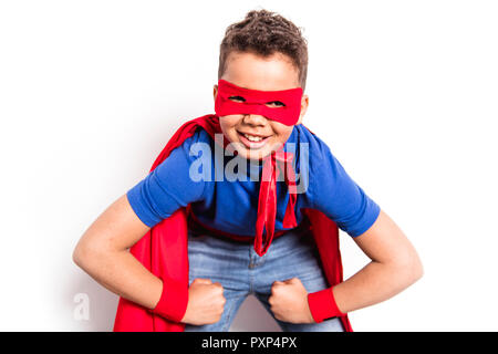 Portrait of boy in superhero costume contre l'arrière-plan gris Banque D'Images