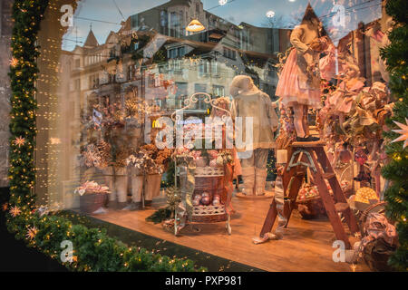 Bâle, Suisse - 25 décembre 2017 : Poupées et jouets sur l'affichage dans le musée du jouet de Noël fenêtre ornée de guirlandes et de boules Banque D'Images