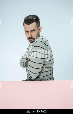 De graves affaires suspectes man sitting at table on blue background studio. Le portrait dans le style minimaliste Banque D'Images