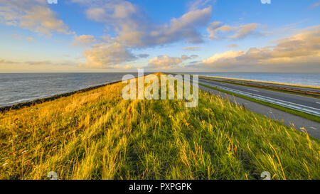 Afsluitdijk dutch endiguer à l'autoroute et piste cyclable au coucher du soleil avec ciel assombri Banque D'Images