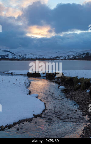 Vue d'hiver de semer l'eau sur un après-midi d'hiver, avec le lac recouvert de glace, et les collines environnantes couvertes de neige Banque D'Images