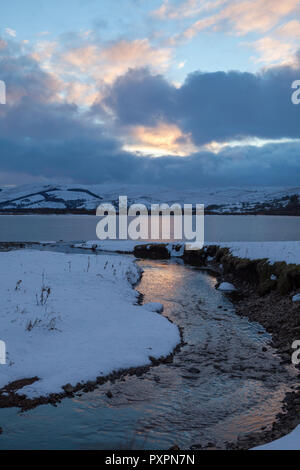 Vue d'hiver de semer l'eau sur un après-midi d'hiver, avec le lac recouvert de glace, et les collines environnantes couvertes de neige Banque D'Images