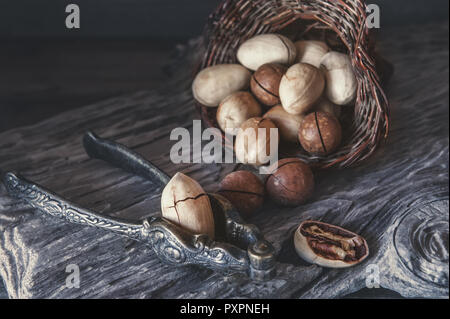 Les noix de macadamia et noix de pécan avec un appareil pour hacher les noix sur un fond de bois. Banque D'Images