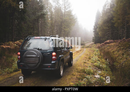 Un 4x4 Jeep hors route lecteurs à travers une forêt dans les Highlands d'Ecosse UK Banque D'Images