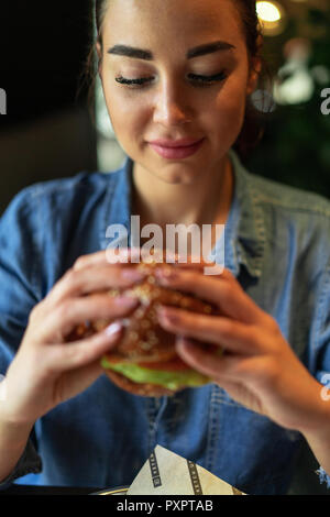 Young attractive brunette woman holding burger juteux. Banque D'Images