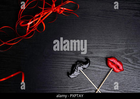 Close up de moustache et femelle, rouge lèvres bonbons, décoré de ruban rouge sur fond de bois noir, le désherbage et l'amour concept Banque D'Images