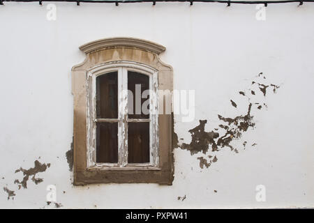 Déshabille de cadre en bois de la fenêtre avec un petit arc, qui est dans un cadre orné de pierres. La façade blanche de la maison avec des pièces détachée altérés. Banque D'Images