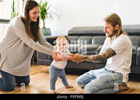 Bébé fille assistance parents prendre Premiers pas à la maison Banque D'Images