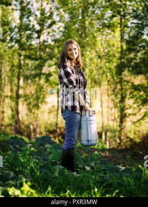 Portrait of smiling farmer avec arrosoir sur un champ Banque D'Images