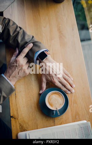 Mature businessman sitting in coffee shop, contrôle de temps Banque D'Images