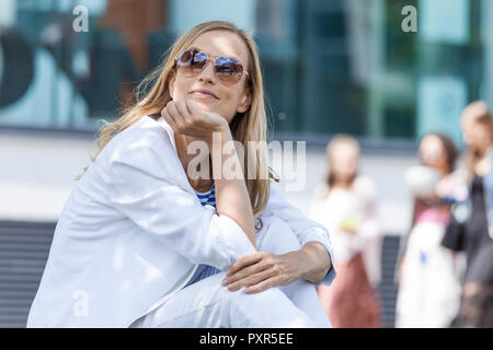 Smiling blonde woman, hand on chin Banque D'Images