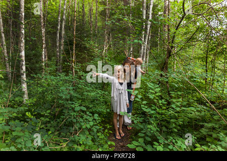 Girl hiking dans les bois montrant la façon de mère et petit frère Banque D'Images