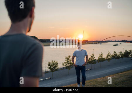 Deux amis regardant le coucher du soleil sur la rivière Banque D'Images